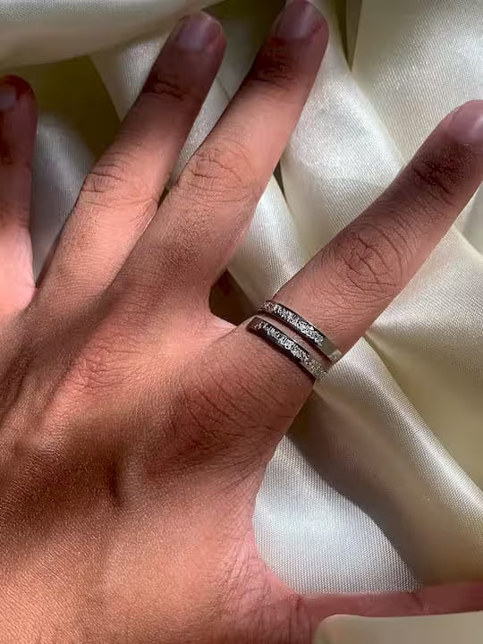 Hand wearing a silver ayatul kursi ring on a white fabric background