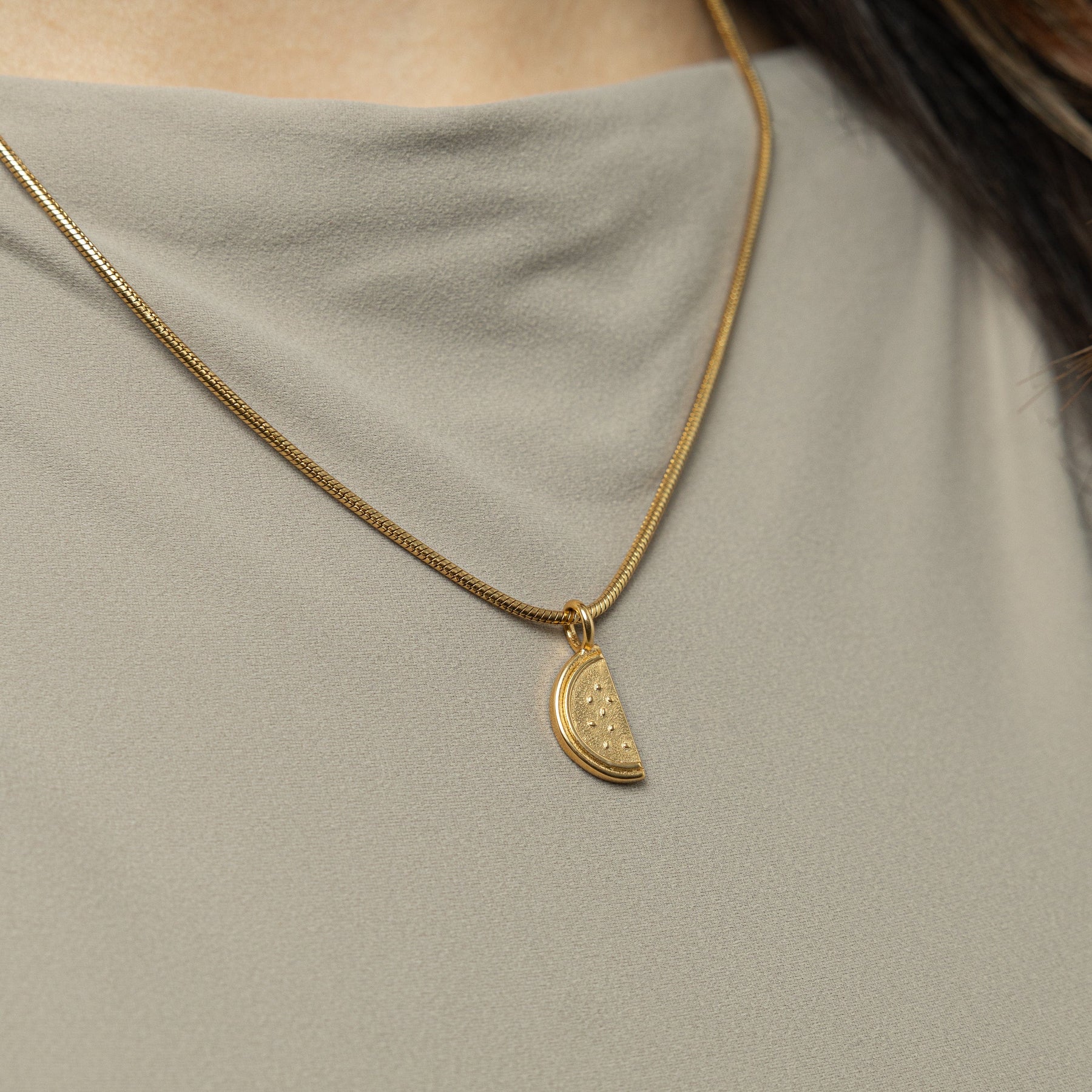 Gold palestine necklace with a pendant on a person wearing a light gray top