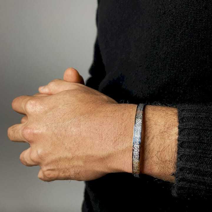 Hand wearing a ayatul kursi bracelet with a blurred background